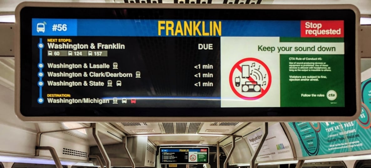 Photo of the interior of a CTA bus featuring two on-board passenger information displays mounted from the ceiling.